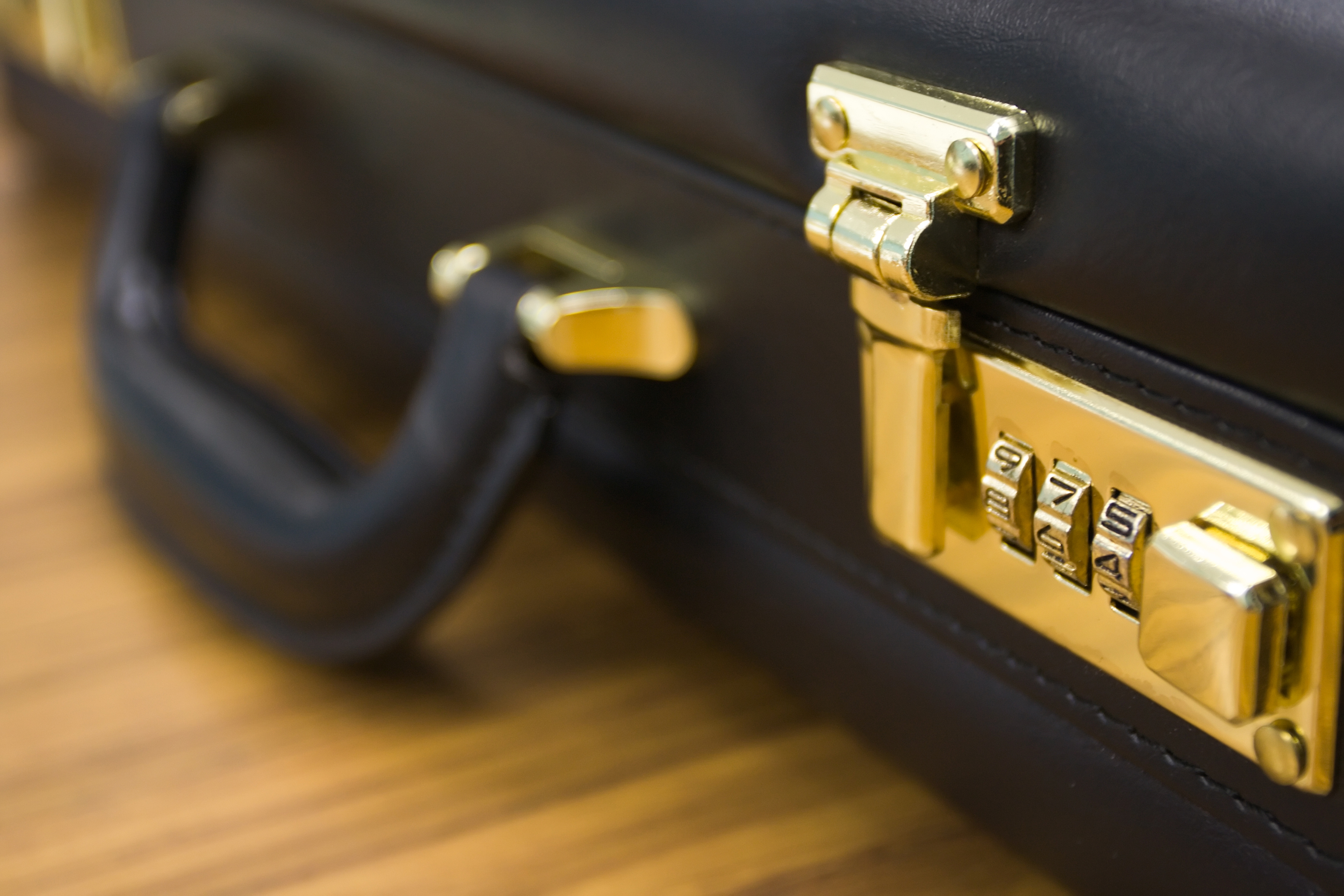 A closeup shot of a brief case, with the combination lock in focus.
