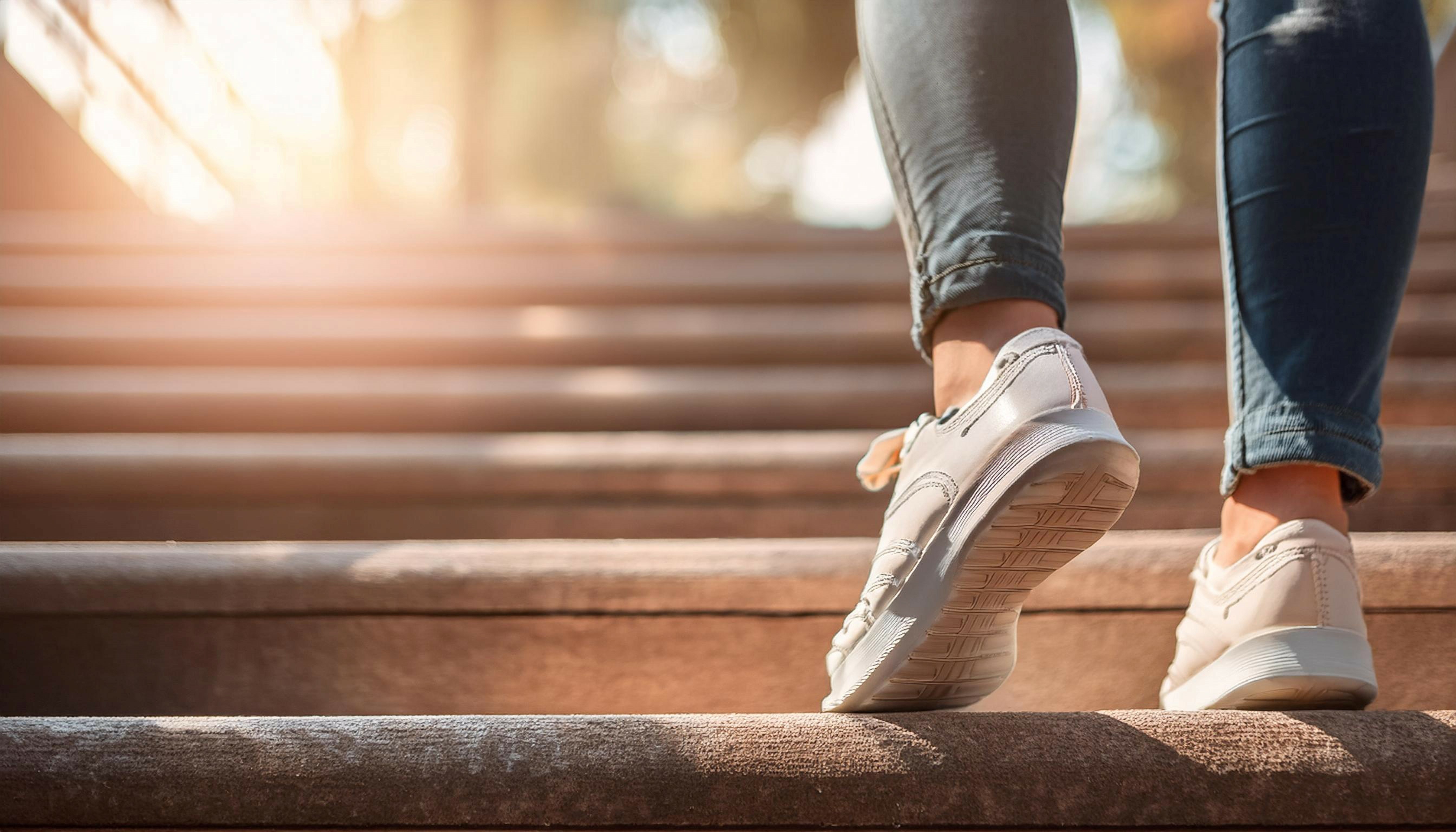 Close up image of a person taking a step on a staircase, symbolizing progress, movement, and action.