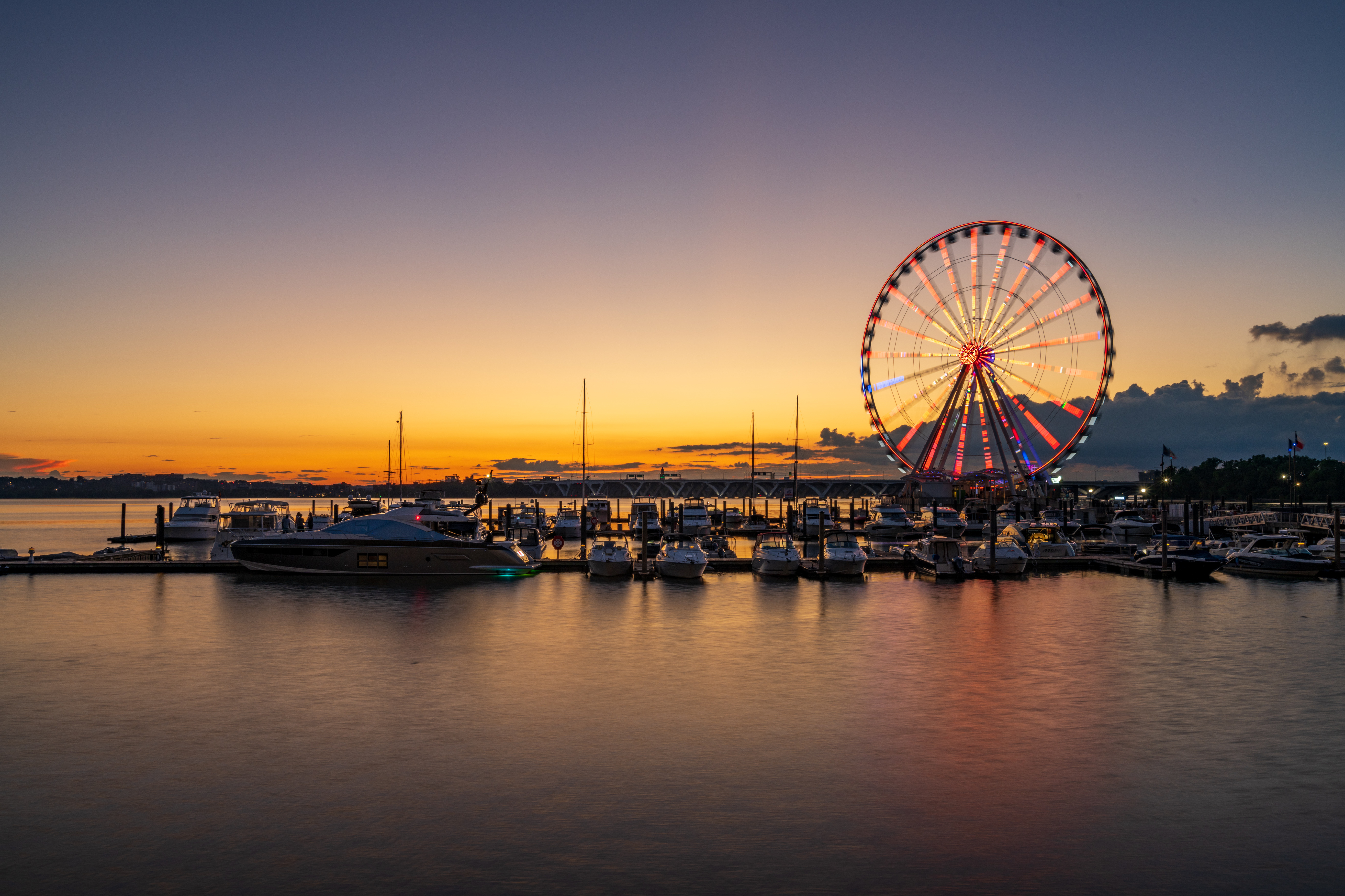 Illuminated ferris wheel at National Harbor near the nation capital of Washington DC at sunset with marina in the foreground